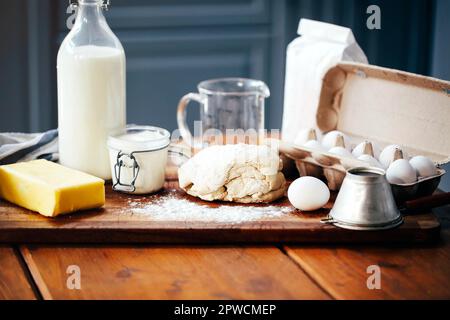 Assorted ingredients for pastry preparation placed on wooden chopping board on table in kitchen Stock Photo