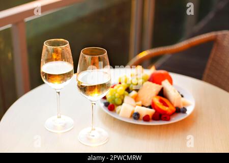 on round table top standing on hotel balcony overlooking on summer forest at sunset. Light snacks for couple on vacation Stock Photo