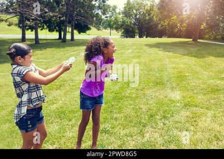 Best friends having fun with balloons. adorable little girls playing with water balloons outdoors. Stock Photo