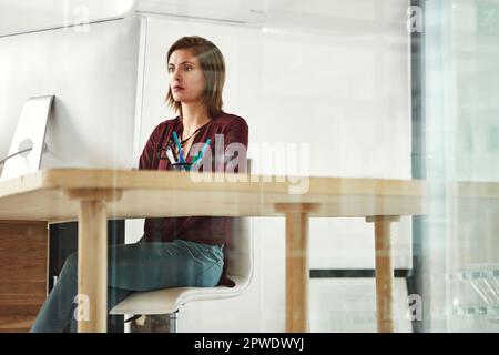 Focused on the task at hand. a young female designer working at her desk in the office. Stock Photo
