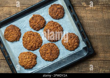 Delicious oatmeal cookies with walnuts on baking sheet, close up, top view Stock Photo