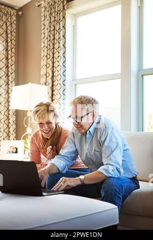 Who knew you could do so much on the internet. a mature couple using a laptop together at home on the sofa. Stock Photo