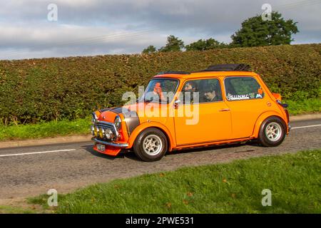 1999, 90s nineties Orange Rover Mini Cooper Car Saloon Petrol 1275 cc; Isolated classic vehicle travelling on a country lane in Congleton, UK Stock Photo