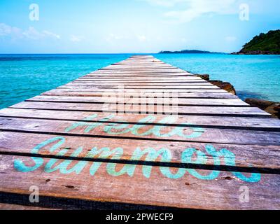 Hello summer concept. Relaxing calligraphy font of "HELLO SUMMER", aqua blue color hand painted on old wooden bridge heading to the tropical sea and o Stock Photo