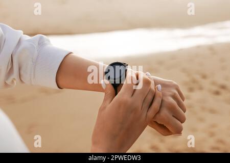Time to start. Sporty young woman using smartwatch, checking fitness tracker, modern gadget with blank screen, mockup Stock Photo