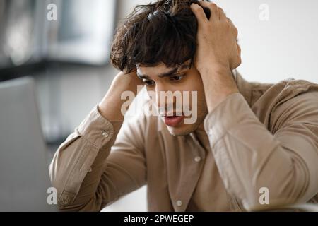 Guy Looking At Laptop Touching Head Having Issue In Office Stock Photo