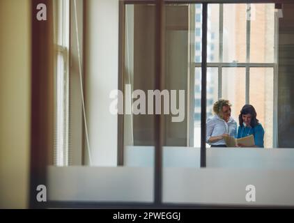 Their ambition knows no bounds. two businesswomen going over paperwork together in an office. Stock Photo