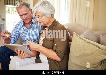 Learning to shop online. a senior couple shopping online on their tablet. Stock Photo