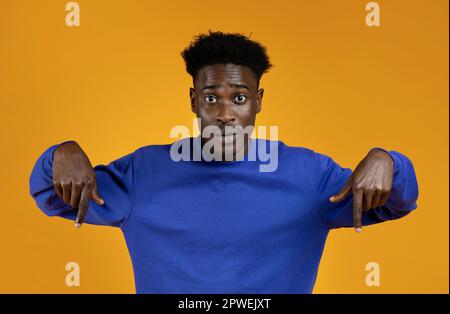 Surprised young african american man pointing down Stock Photo