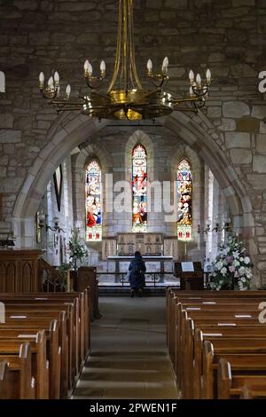 One woman praying in church at the church altar, St Marys Church, Lindisfarne, Holy Island Northumberland UK Stock Photo