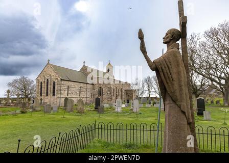 St Marys Church, or St Mary the Virgin Church, with the modern statue of St Aidan in the churchyard, Lindisfarne or Holy Island, Northumberland UK Stock Photo
