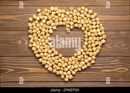 Heart made of crispy popcorn on wooden background Stock Photo