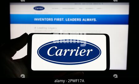 Person holding smartphone with logo of US company Carrier Global Corporation on screen in front of website. Focus on phone display. Stock Photo