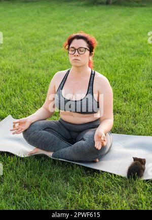 Beautiful fat woman doing yoga on the mat in the park Stock Photo - Alamy