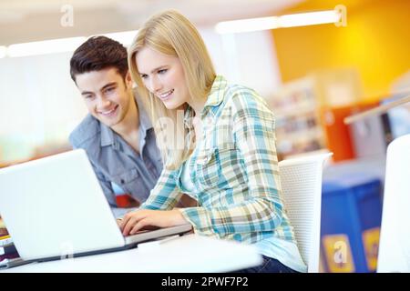 Doing research. Two smiling students helping each other with their homework. Stock Photo