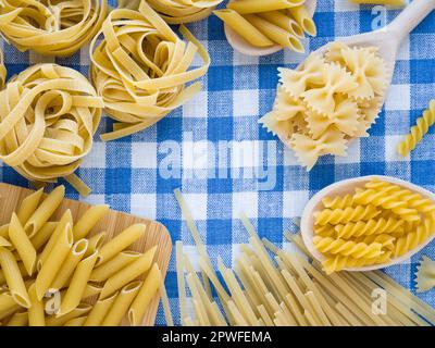 Mixed dried pasta selection on blue and white linen towel as background. Flat lay top view with copyspace for text, logo or other. Colorful and Stock Photo