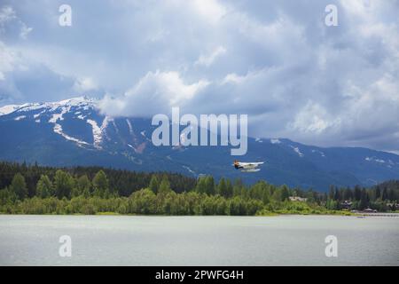 Whistler, Canada - June 3 2019: A Whistler Air floatplane in flight over Green Lake outside the mountain ski resort Whistler, British Columbia. Stock Photo