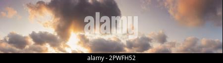 panorama of a sky in warm evening light. massive clouds in orange color at sunset Stock Photo