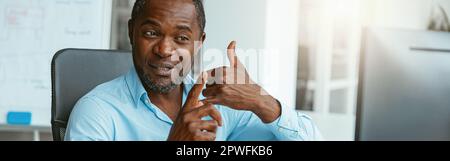 African businessman using sign language while talking online with client sitting in office Stock Photo