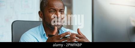 Busy african businessman making videocall to client while sitting in modern office Stock Photo