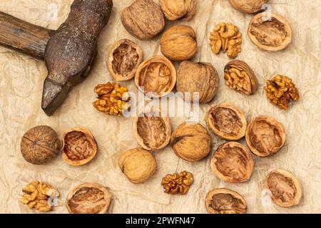 Old rusty hammer and cracked walnuts. Shells, nut kernels and whole nuts on crumpled paper. Flat lay Stock Photo