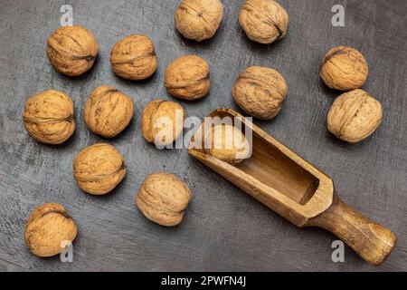 Whole nuts and a wooden scoop on a brown background. Flat lay Stock Photo