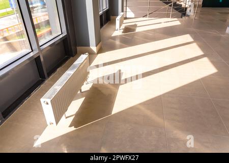 Vertically installed central heating radiator on the floor at the fully ...