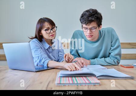 Young teenage male studying languages with teacher in classroom Stock Photo