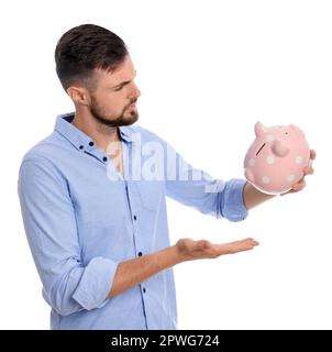 Confused young man with empty piggy bank on white background Stock Photo