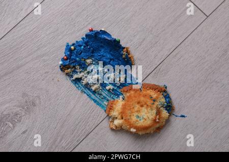 Dropped and smashed cupcake with cream on floor. Troubles happen Stock Photo