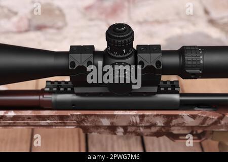 Closeup view of modern powerful sniper rifle with telescopic sight on blurred background Stock Photo