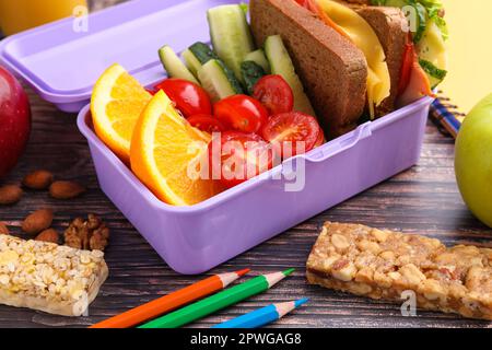 Lunch box with healthy food for schoolchild and different stationery on wooden table, closeup Stock Photo