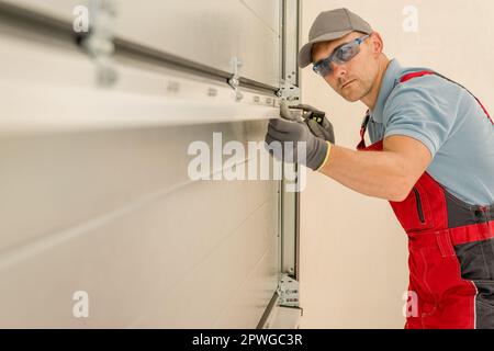 Installing Brand New Residential Garage Doors by Professional Caucasian Technician in His 40s. Stock Photo