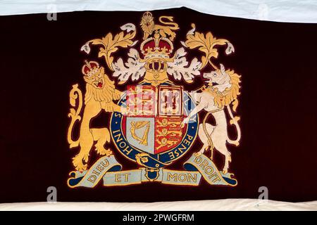 Detail of the royal coat of arms on a throne chair cover, where King Charles III and the Queen Consort visited the Royal College of Needlework at Hampton Court Palace in East Molesey, Surrey. Picture date: Tuesday March 21, 2023. Stock Photo