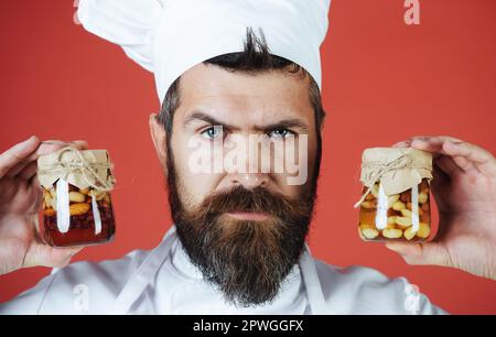 Bearded chef holding jar with honey nuts. Healthy food and sweet meals. Nutrition concept. Chef with jars of mixed nuts in honey. Male cook with jars Stock Photo