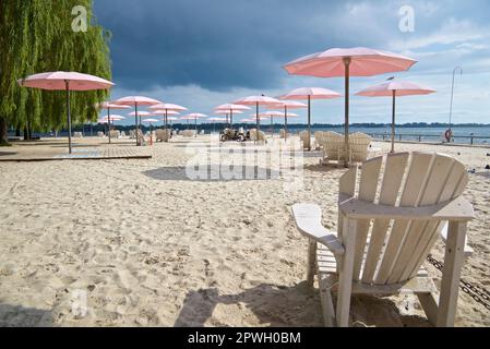 Cloudy sky on the beach with the pink beach umbrellas and Adirondack chairs Stock Photo