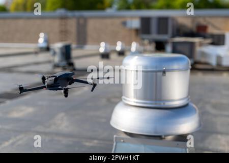 Drone being used to perform an aerial inspecting of HVAC RTU equipment on a commercial roof. Stock Photo