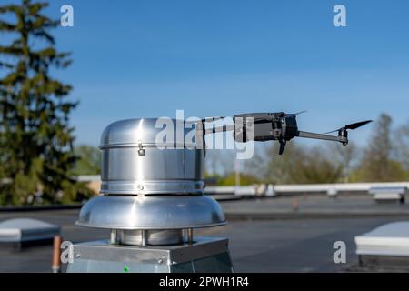 Drone being used to perform an aerial inspecting of HVAC RTU equipment on a commercial roof. Stock Photo