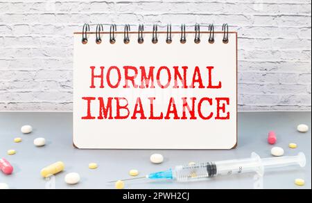 Medical concept. On a brown surface lies a stethoscope, pills and a notepad with the inscription - Hormones Imbalance. Stock Photo