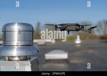 Drone being used to perform an aerial inspecting of HVAC RTU equipment on a commercial roof. Stock Photo