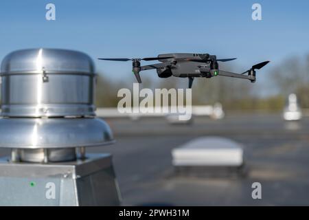 Drone being used to perform an aerial inspecting of HVAC RTU equipment on a commercial roof. Stock Photo