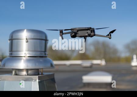 Drone being used to perform an aerial inspecting of HVAC RTU equipment on a commercial roof. Stock Photo