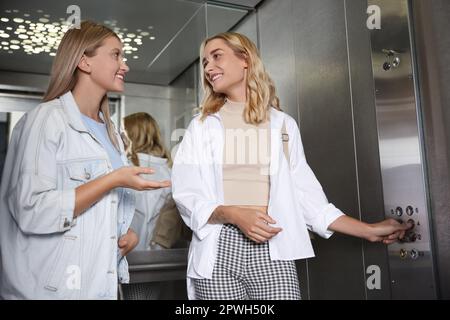 Happy young women talking in modern elevator Stock Photo