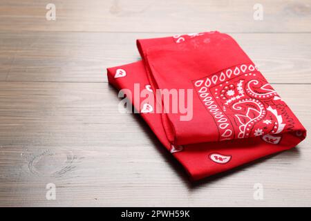 Folded red bandana with paisley pattern on wooden table, space for text Stock Photo