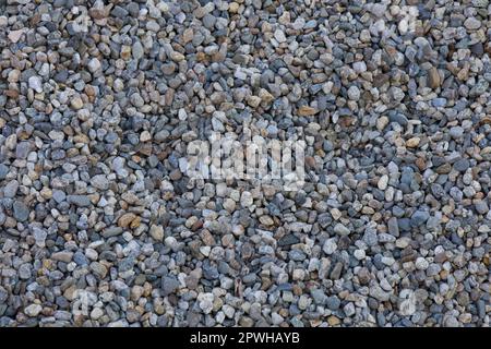 Background or backdrop of stone pebbles. Smooth, round pebbles. Rock textured background. Stone closeup. Dark gray pebbles found outdoors. Stock Photo