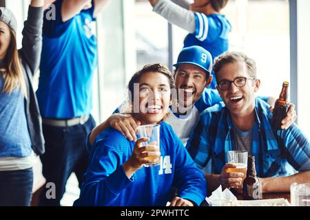 This is our idea of having fun. A group of excited friends cheering on their favourite team at the bar. Stock Photo