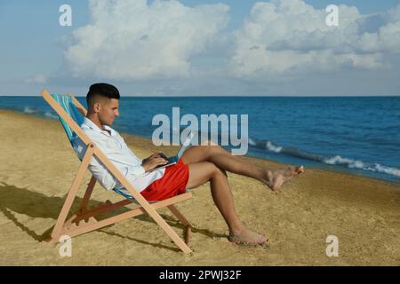 Man working with laptop on beach. Business trip Stock Photo