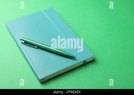 New stylish planner with hard cover and pen on green background Stock Photo