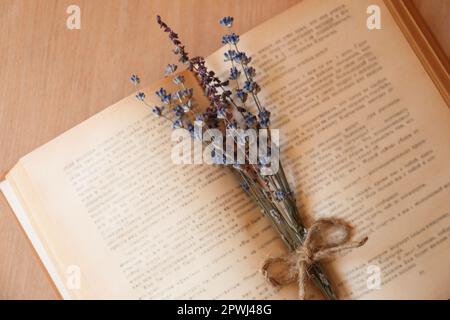 Open book with bunch of dried flowers on wooden table, closeup Stock Photo