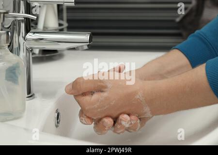 Man washing hands with soap over sink in bathroom, closeup Stock Photo